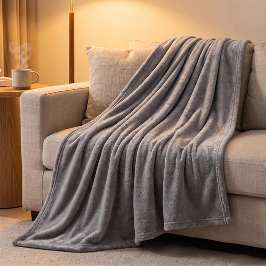 Graue Fleece Kuscheldecke über die Sofaecke drapiert im gemütlichen Wohnzimmer
