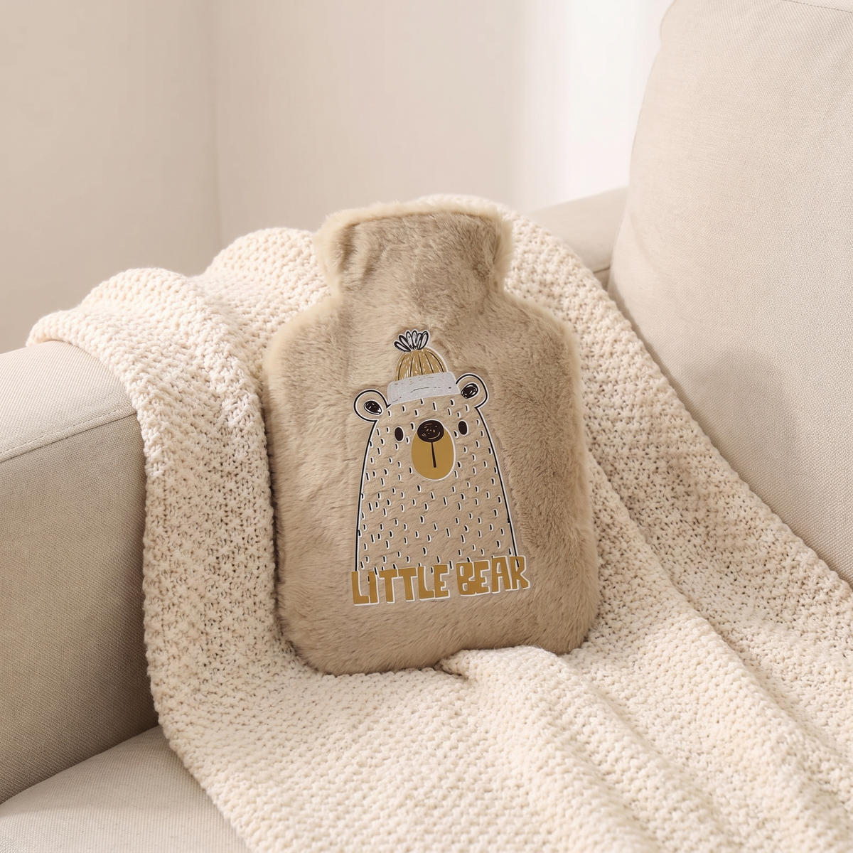 Mini Wärmflasche mit Plüschbezug in Braun auf einer Kuscheldecke