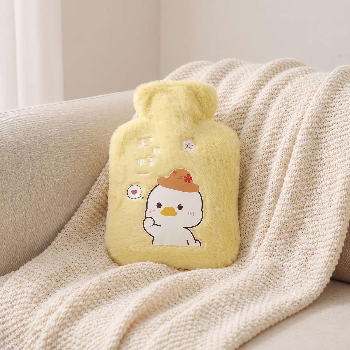 Mini Wärmflasche mit Plüschbezug in Gelb auf einer Kuscheldecke
